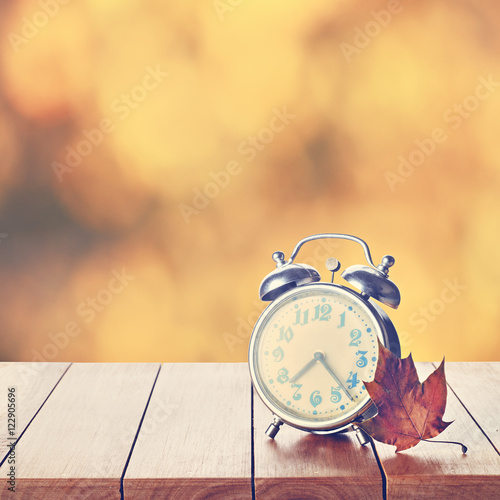 Vintage alarm clock on autumn season background