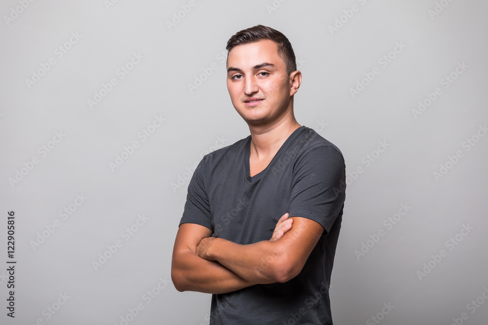 Portrait of a smiling man standing with hands crossed over gray background Portrait of a smiling man standing with hands crossed over gray background