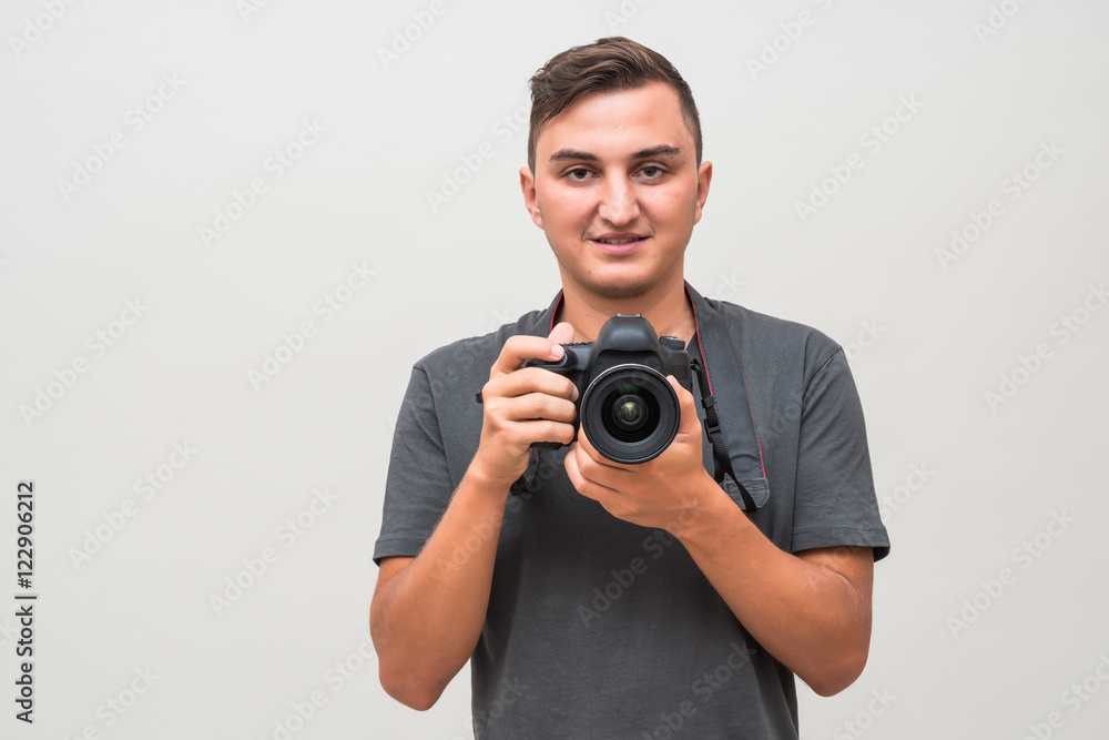 Portrait of a smiling handsome man holding camera isolated on a gray background Portrait of a smiling handsome man holding camera isolated on a gray background