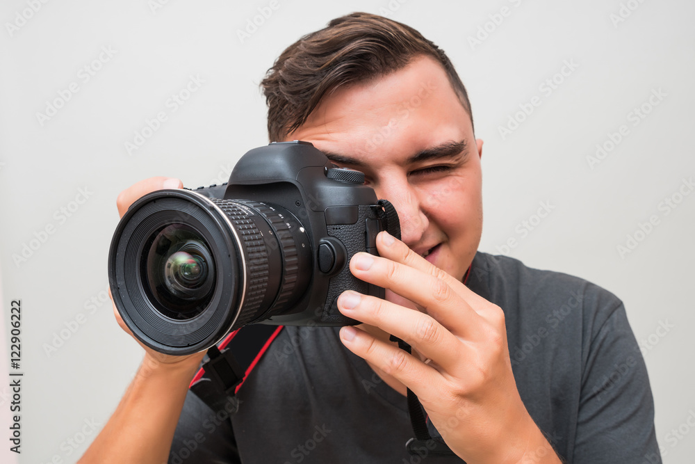 Portrait of a male photographer with camera taking photo isolated on a gray background Portrait of a male photographer with camera taking photo isolated on a gray background