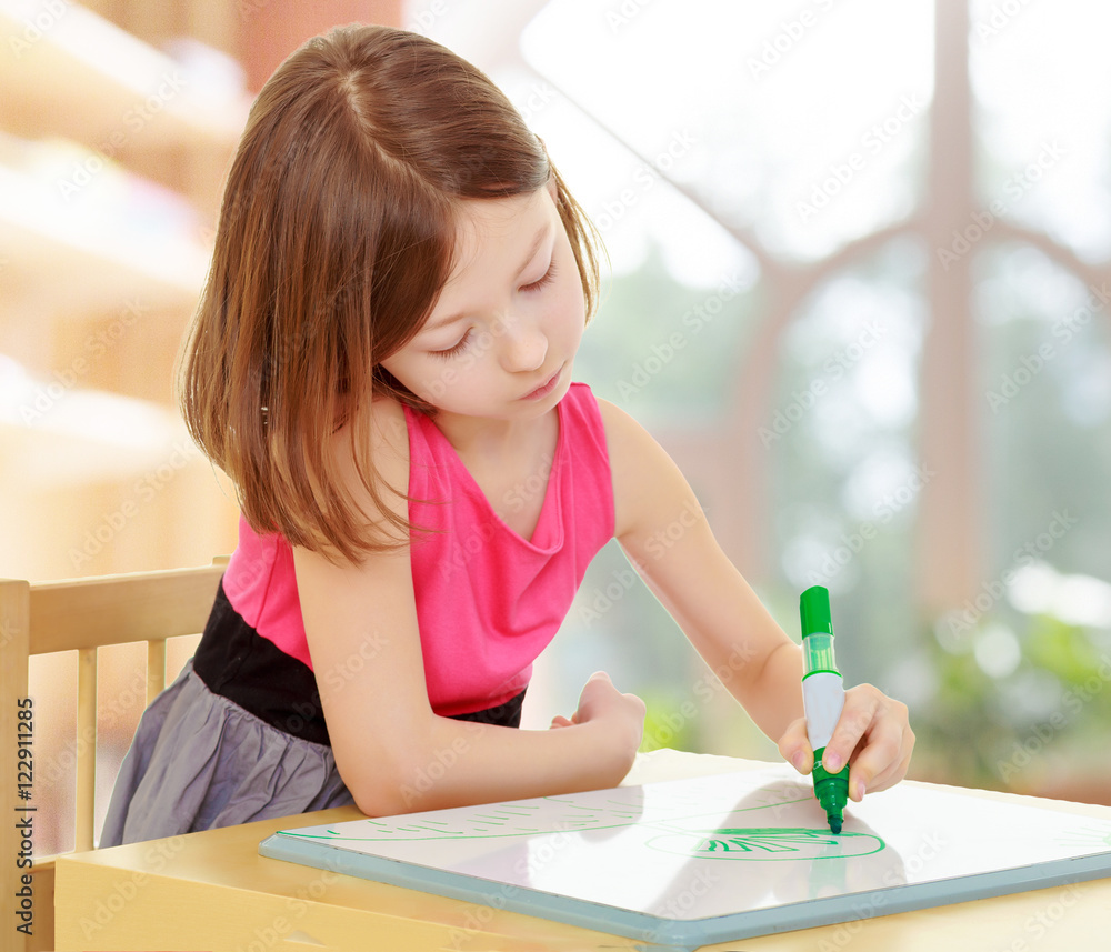 little girl draws with marker sitting at the table. little girl draws with marker sitting at the table.