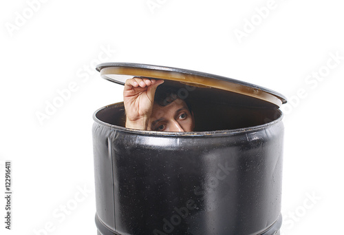 young man hides in a barrel. guy lifted the lid barrels and looks cautiously. the concept of avoiding problems. isolated on white background. photo