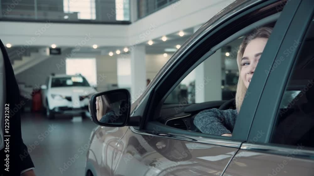 Unrecognizable Sales Manager Gives the Client the Keys from the Car. Then smiling woman customer look straight at the camera Unrecognizable Sales Manager Gives the Client the Keys from the Car. Then smiling woman customer look straight at the camera