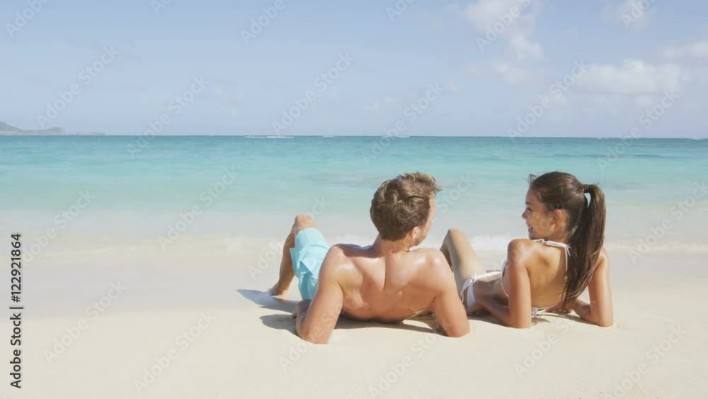 Beach sun tan couple on summer vacation holiday Vacations suntan concept - adults lying down tanning on luxury exclusive paradise beach. Asian woman, Cacuasian man. RED EPIC SLOW MOTION 96 FPS. Beach sun tan couple on summer vacation holiday Vacations suntan concept - adults lying down tanning on luxury exclusive paradise beach. Asian woman, Cacuasian man. RED EPIC SLOW MOTION 96 FPS.