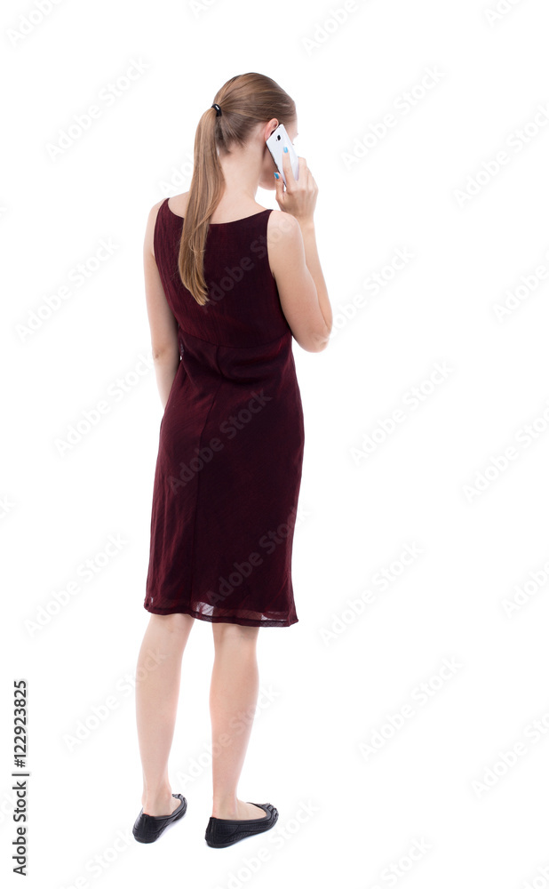Fototapeta premium back view of a woman talking on the phone. backside view of person. Rear view people collection. Isolated over white background. A girl in a burgundy dress talking on the phone.