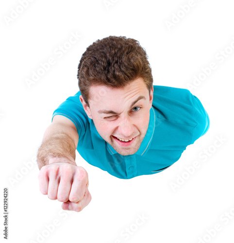 Flying man front view. Smiling curly-haired guy is flying in Superman pose. Isolated over white background. Curly boy in superman pose winking