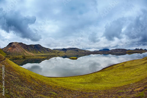 Lake coast with mountain reflection at the cloudy day, Iceland