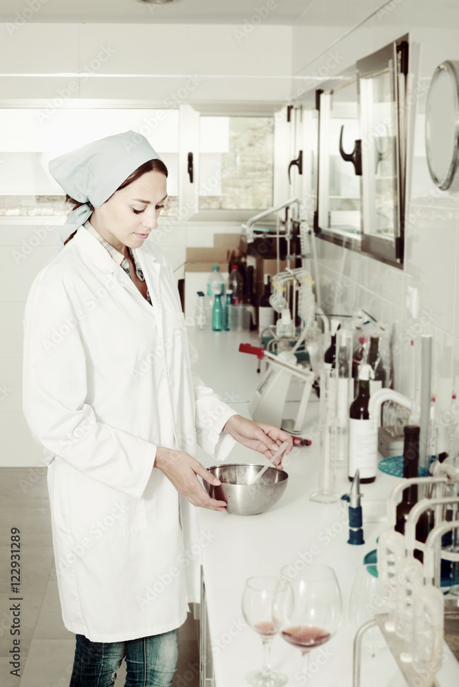 Female checking quality of wine in chemical laboratory