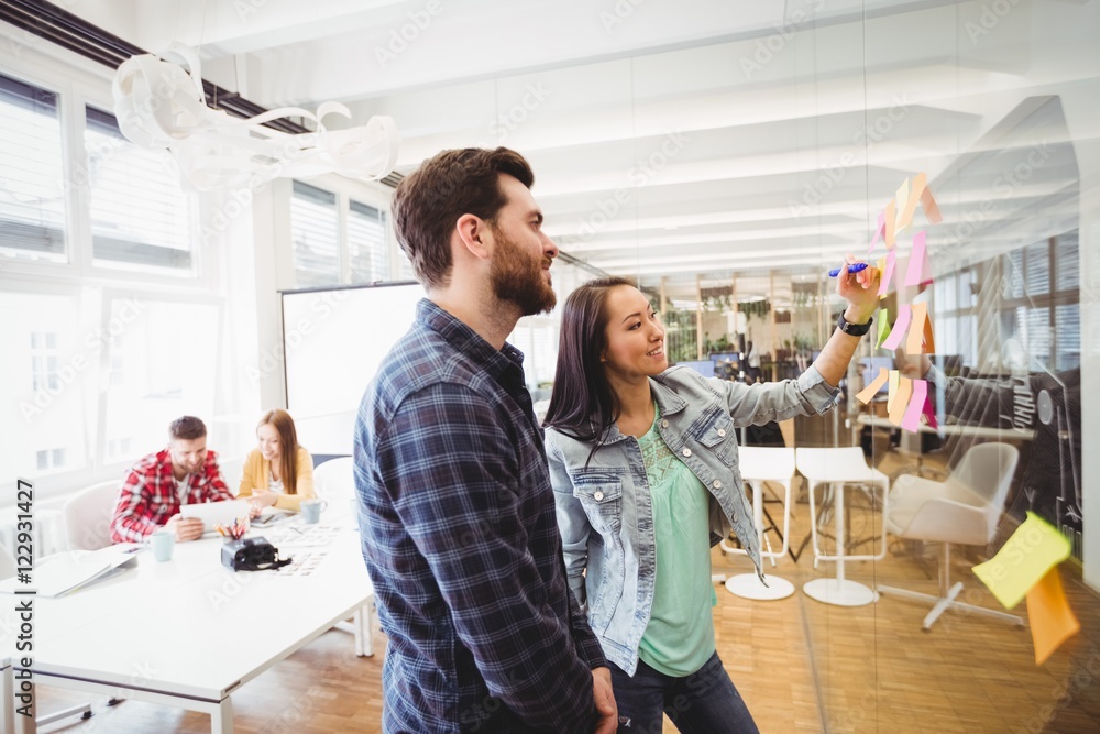 business people looking at multi colored sticky notes business people looking at multi colored sticky notes