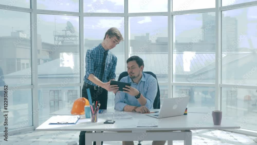 Boss discuss project with employee, gives advice, using digital tablet in new modern office. 4K.