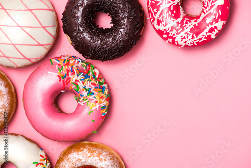 Valokuva Donuts with icing on pastel pink background. Sweet donuts.