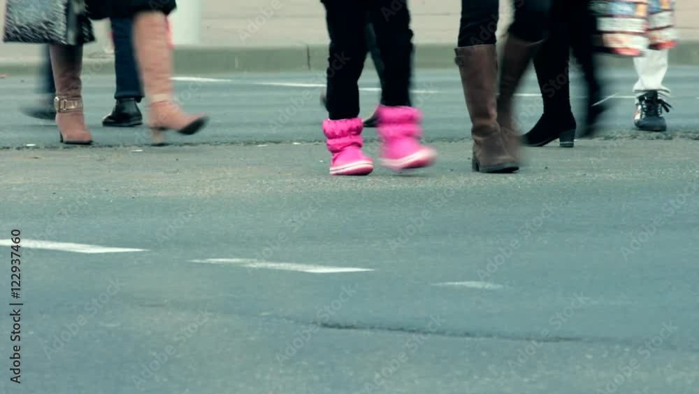 Legs of people who cross the street at a pedestrian crossing. Legs of people who cross the street at a pedestrian crossing.