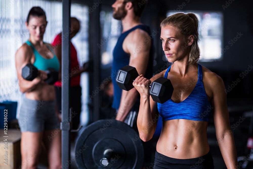 Confident woman holding dumbbells in gym