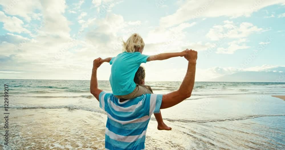Father and son walking and playing having fun on the beach at sunset Father and son walking and playing having fun on the beach at sunset