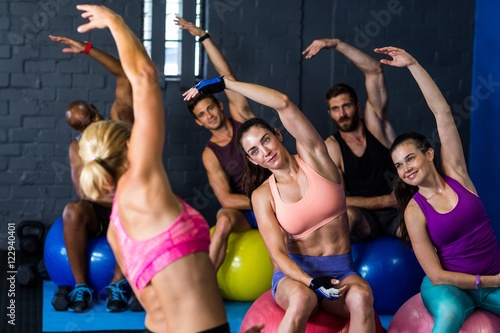 Fototapeta Naklejka Na Ścianę i Meble -  Athletes exercising with instructor in gym