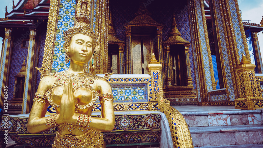 Vintage retro effect filtered hipster style image of Golden angel statue of the Emerald Buddha temple(Wat phra kaew) and Royal Grand Palace ,Bangkok,Thailand.