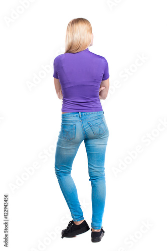 back view of standing young beautiful woman. girl watching. Rear view people collection. backside view of person. Long-haired blonde in the purple shirt stands with his arms crossed.