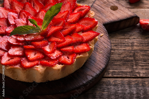 Tart with strawberries and whipped cream on wooden vintage table