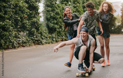 Group of friends having fun outdoors with skateboard