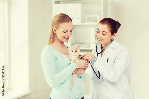 happy woman with cat and doctor at vet clinic