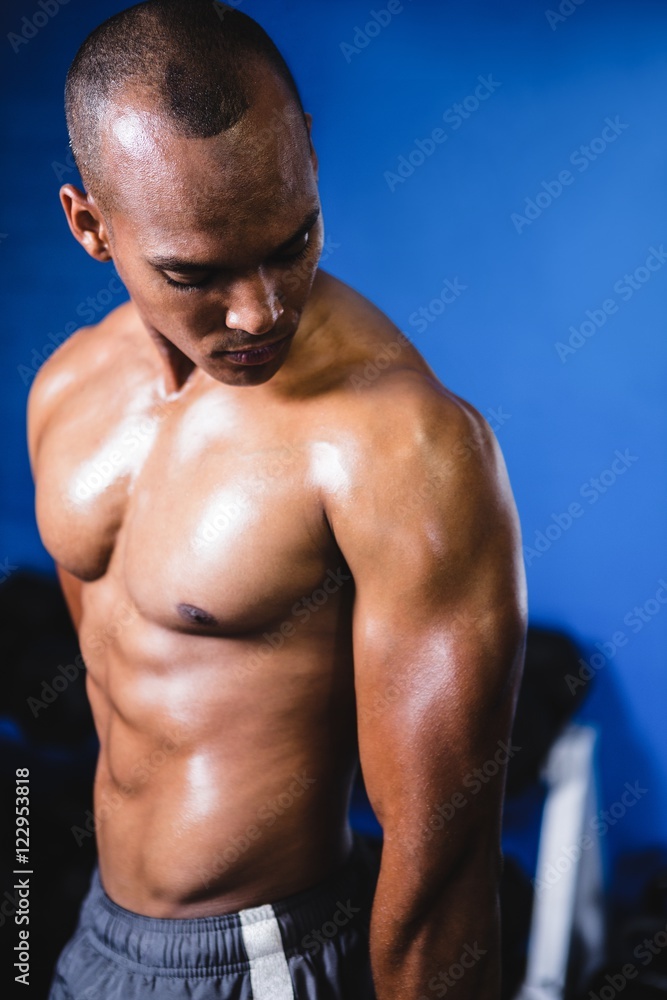 Muscular man looking at arm in gym Muscular man looking at arm in gym