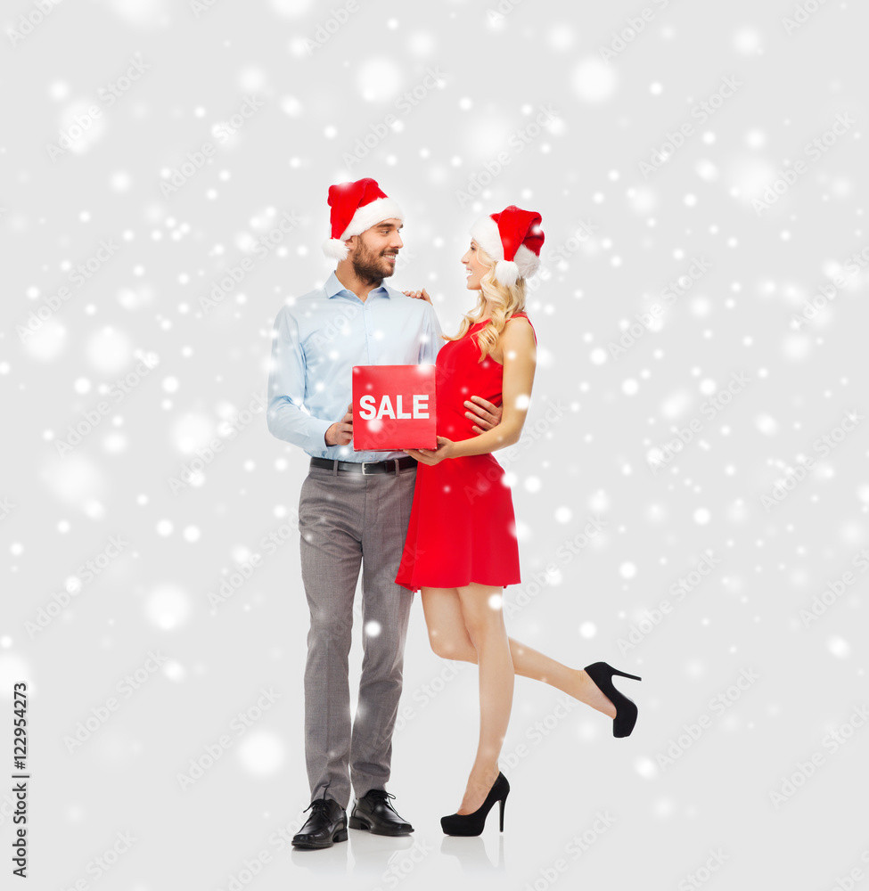 Obraz premium happy couple with red sale sign over snow