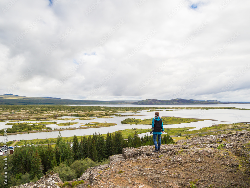 Woman is standing at a cliff in front of the Thingvellir Nationa