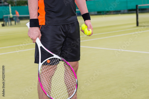 Close-up of male holding tennis balls and racket © kolotype