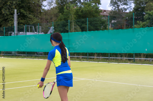 Pretty female tennis player wearing a sportswear warming up befo