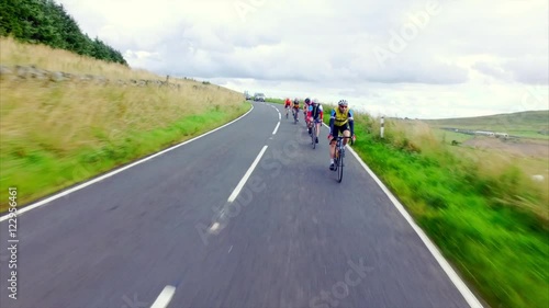 A stabilised cam of a group of cycling athletes out on a training ride on country roads in the UK countryside on a sunny day. 