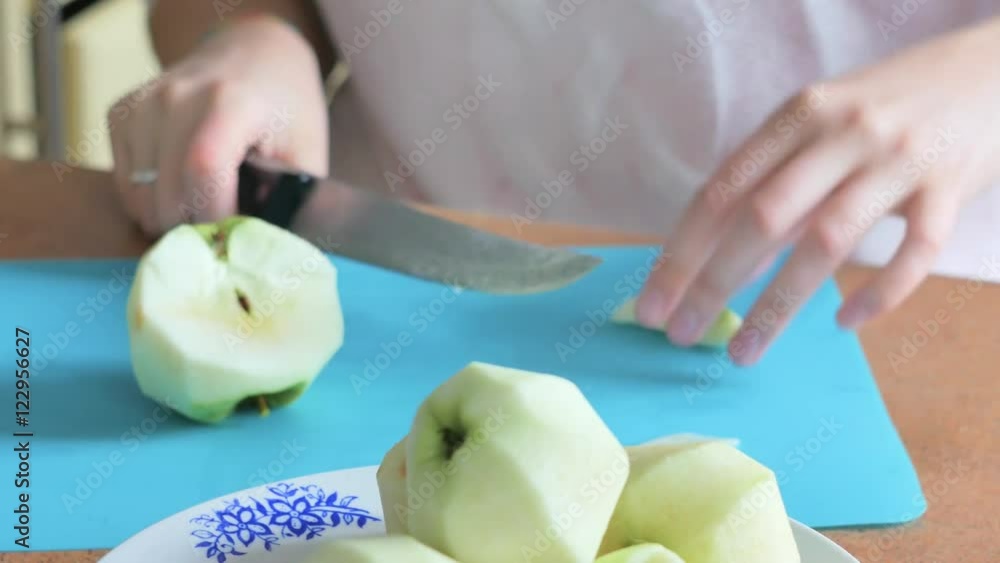 Slicing apple. Cutting apple. Cook cut apple at wooden plank in kitchen. Slicing peeled apple. Apple slice. A knife cutting apple in slices. Healthy food. Vegetarian food