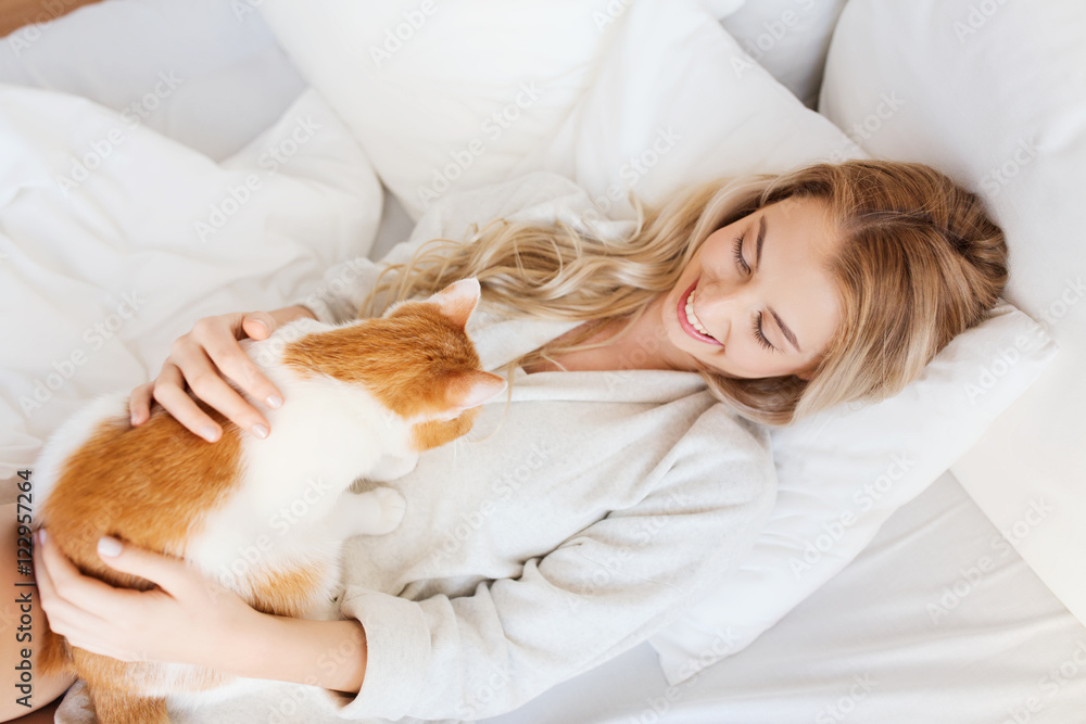 happy young woman with cat in bed at home happy young woman with cat in bed at home