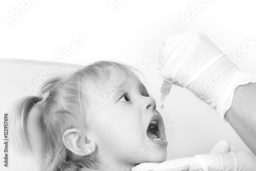 Canvas Print The little girl on reception at the doctor receives the polio va