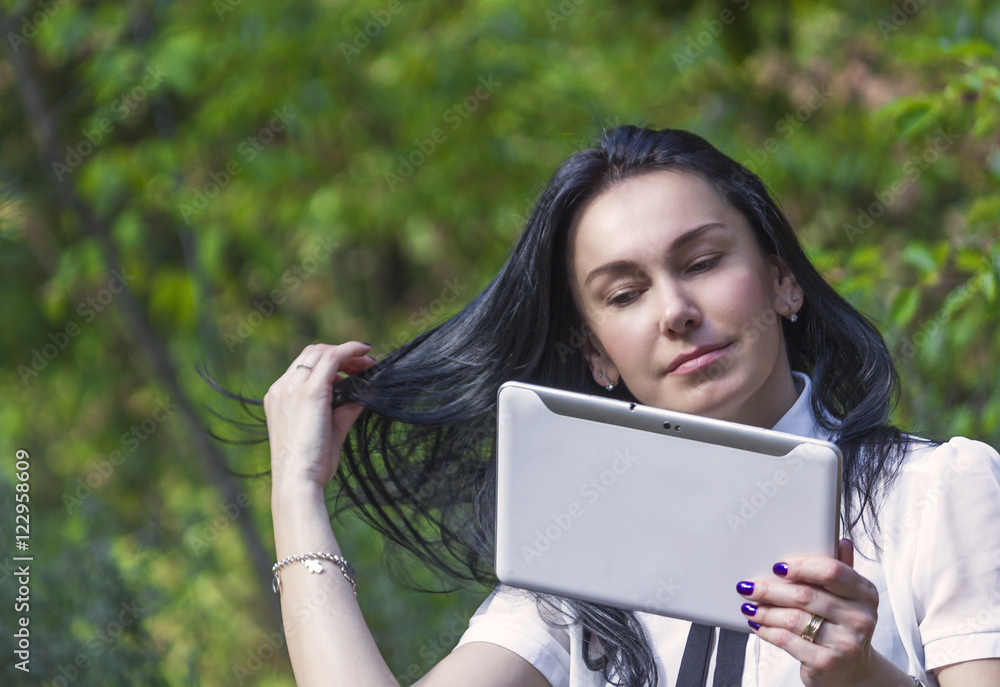 Young woman standing in the woods with her white tablet Young woman standing in the woods with her white tablet