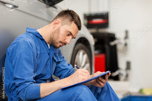 auto mechanic man with clipboard at car workshop