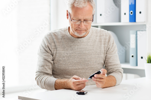 Fotografía senior man with glucometer checking blood sugar