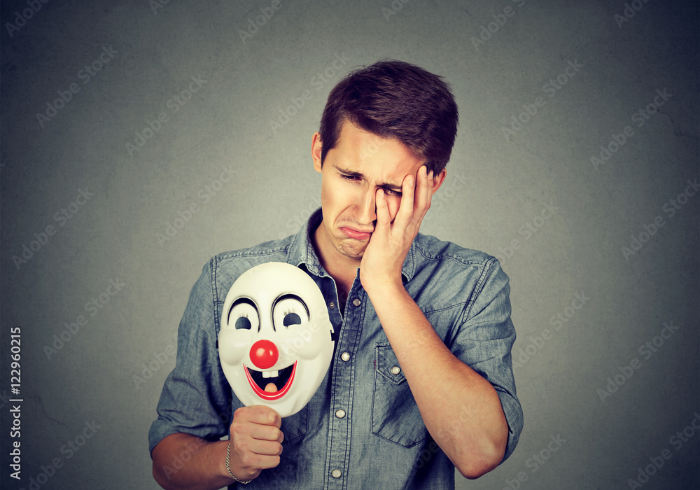 Young sad man with happy clown mask foto de Stock | Adobe Stock