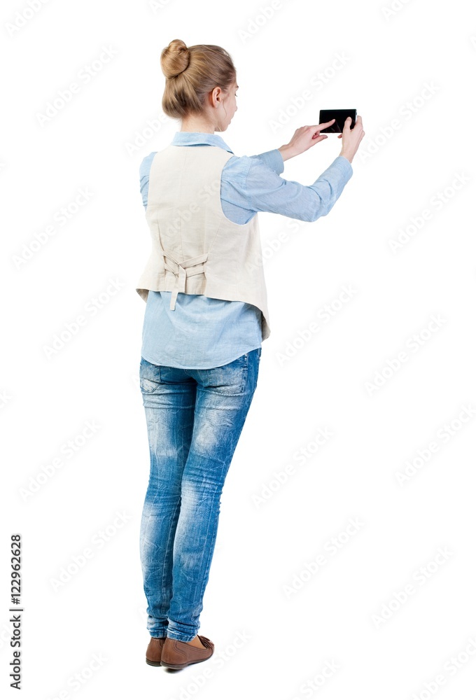 back view of standing young beautiful woman in vest and using a mobile phone. girl watching. Rear view people collection. backside view of person. Isolated over white background. Girl in back view of standing young beautiful woman in vest and using a mobile phone. girl watching. Rear view people collection. backside view of person. Isolated over white background. Girl in