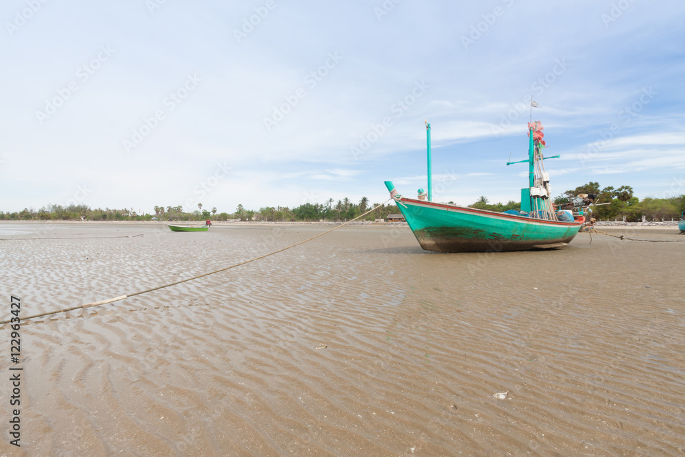 Wooden fishing boat on the  low tide beach.