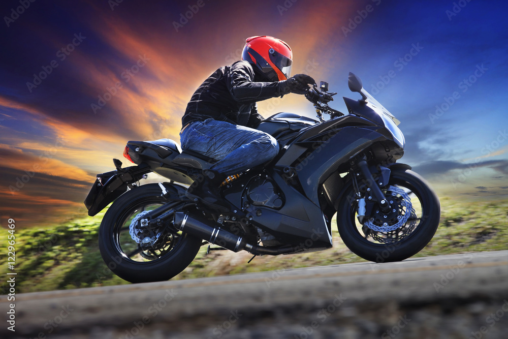 Obraz premium young man riding motorcycle on curve of asphalt country road aga