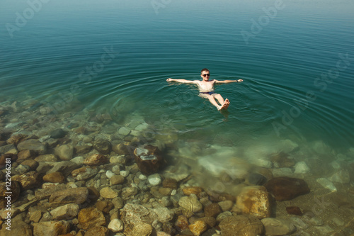 Man in crystal clear water Dead Sea. Tourism recreation concept