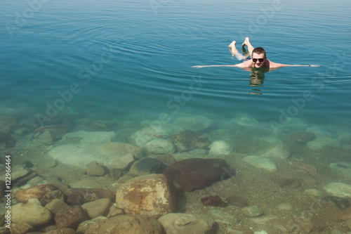 Man lying on water Dead Sea enjoying vacation .Tourism recreation, healthy lifestyle concept. Copy space