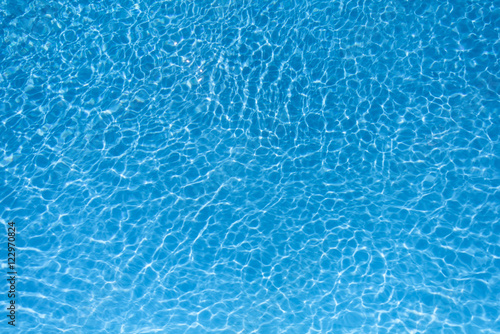 Blue water surface in swimming pool with sun reflection..