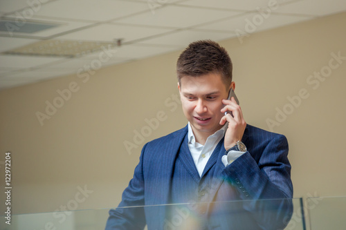 Time for myself in a midst of work day. Young businessman reading something on his phone and smiling cheerfully