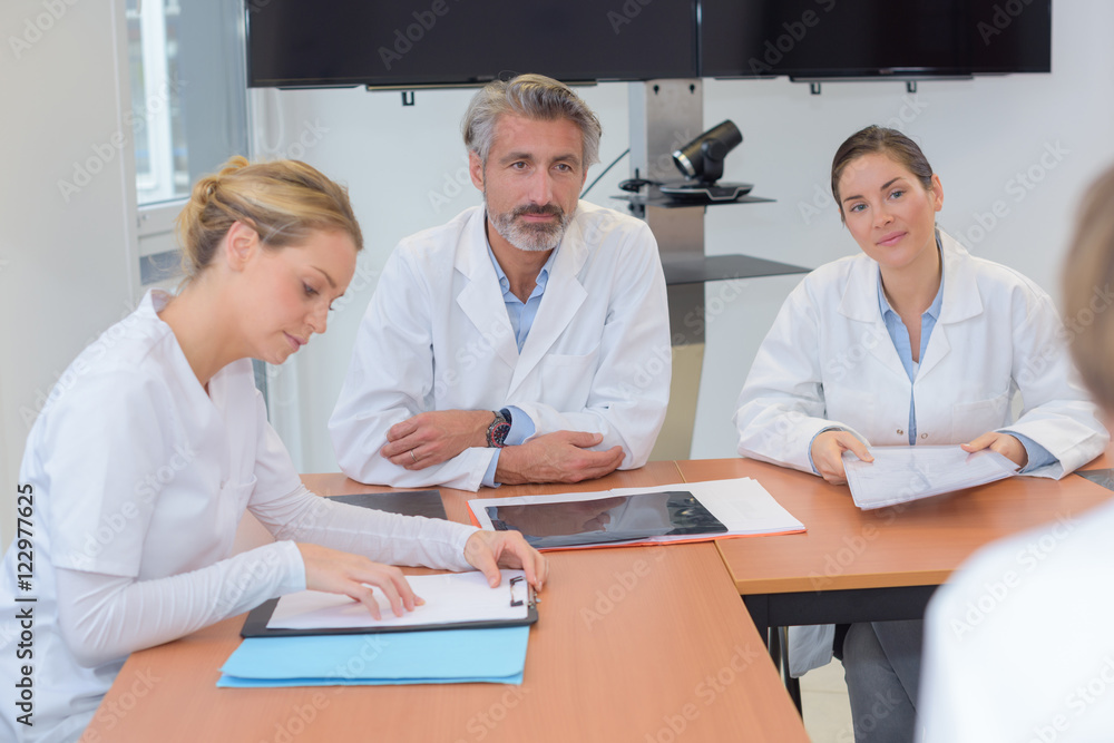 Fototapeta premium Medics sat around table in discussion