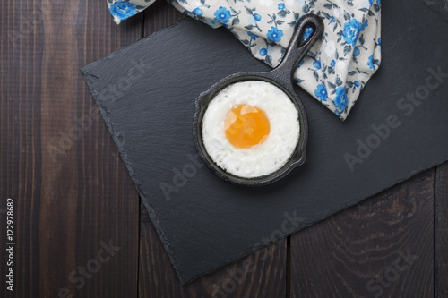Obraz jajko sadzone na małym czarnym i drewnianym tle cocotte