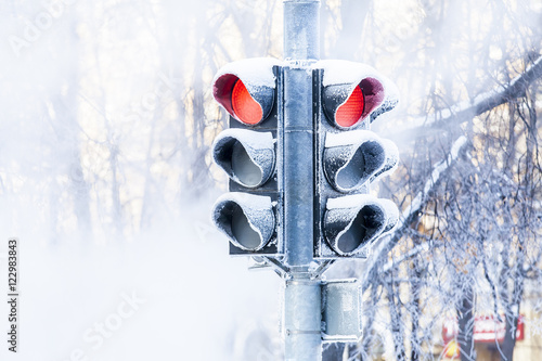 Frozen traffic lights on the winter street. Green and red light. Snow, frost and steam. 