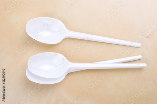 Plastic disposable white spoons on a wooden table photo