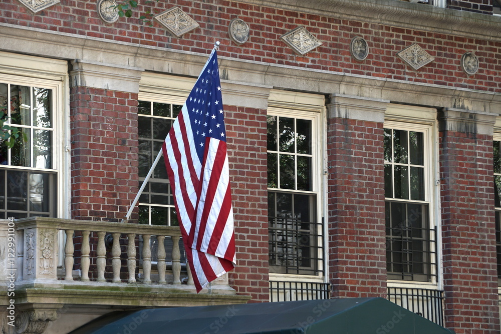 American flag hangs above the doorway to a traditional style urban building. Patriotic support
