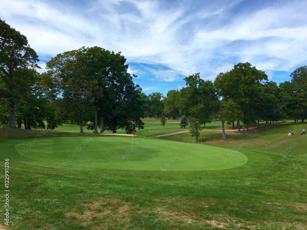 Overlooking the green on a beautiful golf course on a partly cloudy autumn day. Perfect sport activity for young and old. Overlooking the green on a beautiful golf course on a partly cloudy autumn day. Perfect sport activity for young and old.